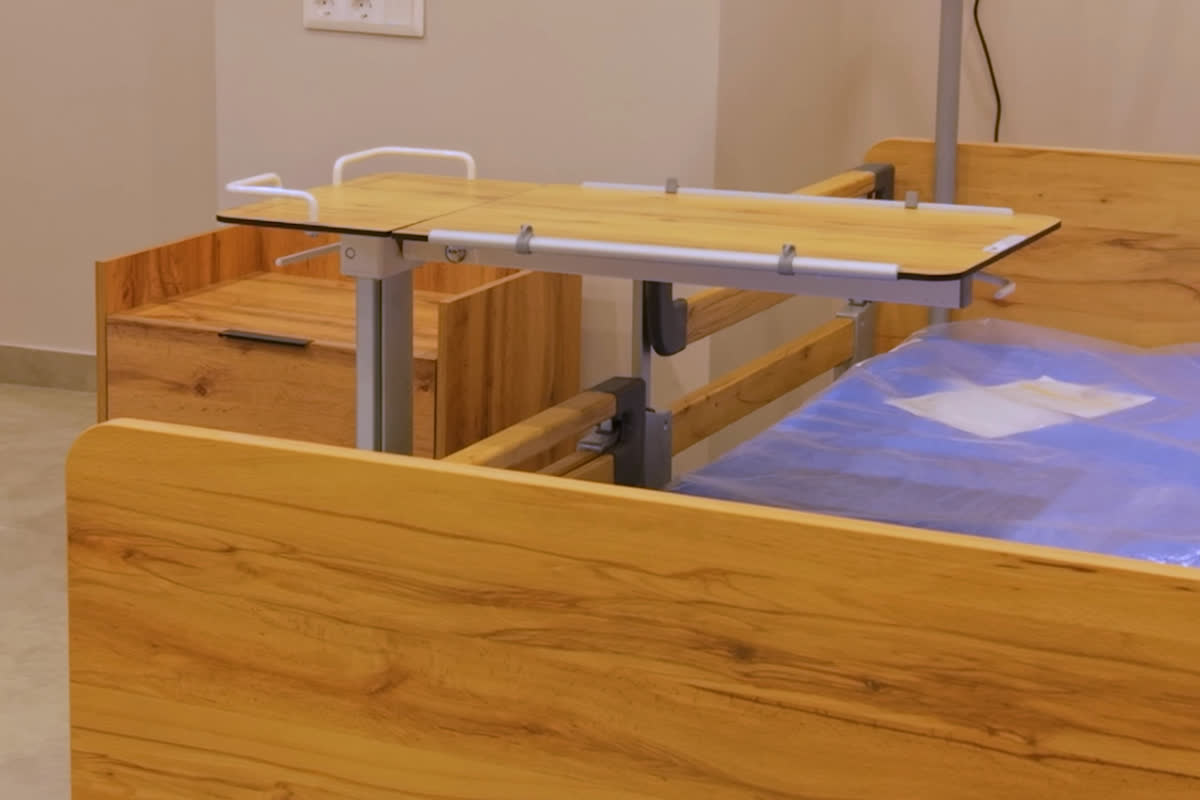 An adjustable bed with an overbed table in a patient room